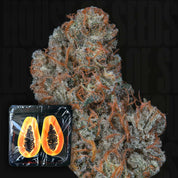 Riviera Drip von Nine Weeks Harvest: eine Cannabis-Knospe mit orangefarbenen Haaren neben einer aufgeschnittenen Papaya in Plastikfolie.